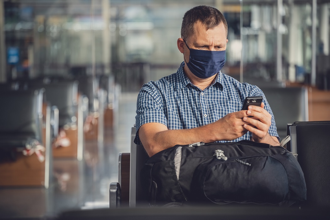 Homem olhando o celular em aeroporto.